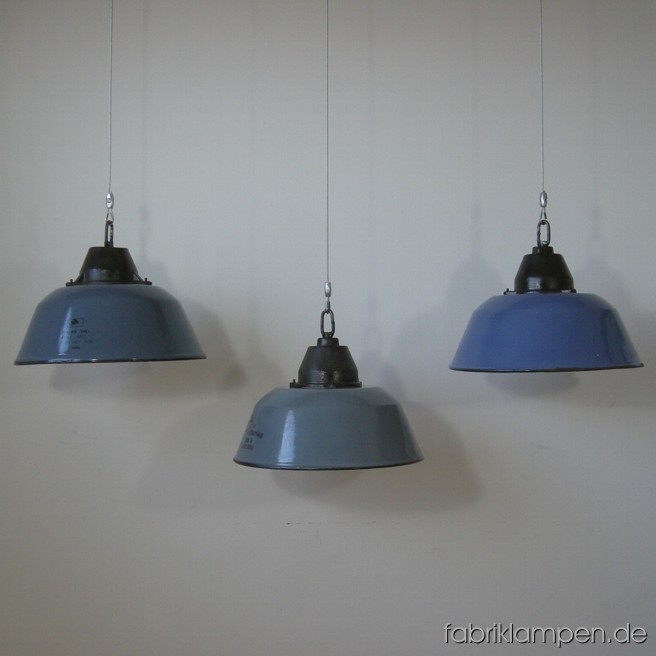3 Stück Emaille Lampen mit Drahtseil-Aufhängung. Material: Gusseisen, blau und grau emeilliertes Stahlblech. Die Lampen haben 10-er Gewinderöhre für die Fassungen, also die Montierung und Elektrifizierung kann einfach durchgeführt werden – gegen 20 EUR Aufpreis (pro Lampe) können wir die Elektrifizierung auch übernehmen. Höhe der Lampen ohne Aufhängung ca. 23 cm, Durchmesser Schirm ca. 36 cm.
