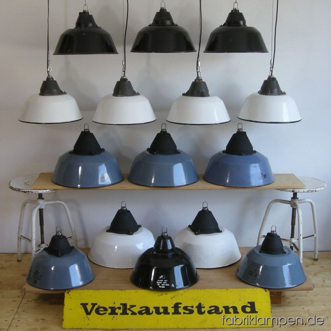Industrielampen in verschiedenen Farben und in zwei Größen. Material: weiss, grau (bläulich) oder schwarz  emailliertes Blech und Gusseisen, mit Drahtseil-Aufhängung.  Höhe Lampen ohne Aufhängeöse ca. 23 oder 28 cm, Durchmesser Schirm ca. 36 oder 41 cm.