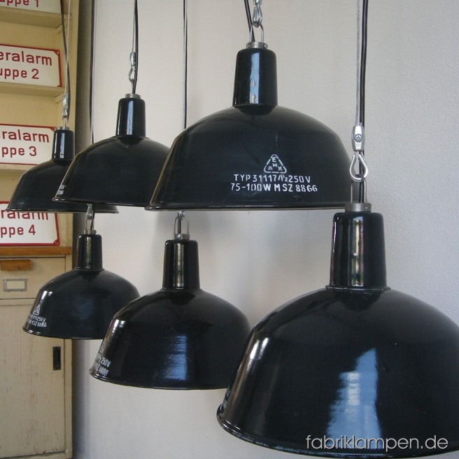 Graue Emaille Industrielampen mit Aufschrift im schönen Originalzustand. Material: grau (bläulich) emailliertes Blech, mit Drahtseil-Aufhängung. Die Lampen sind gereinigt, neu elektrifiziert und getestet – alle Lampen haben eine E27 Fassung, also Sie können die Lampen mit normalen E27 Glühbirnen benutzen.
