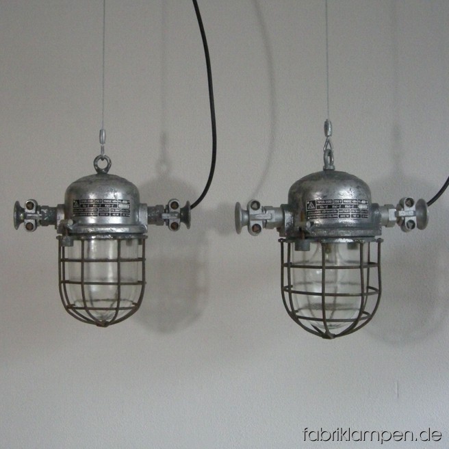 Klassische Industrielampe (Bunkerlampe) mit Aluminiumgehäuse, Stahlgitter und Schutzglas. 20 Stück vorhanden. Die Lampen sind gereinigt, neu elektrifiziert (ausgestattet mit ca. 2 m Kabel) und getestet. Gesamthöhe: ca. 30 cm, Durchmesser ohne Ohren ca. 18 cm. Auch in kürzerer Version auf Lager.