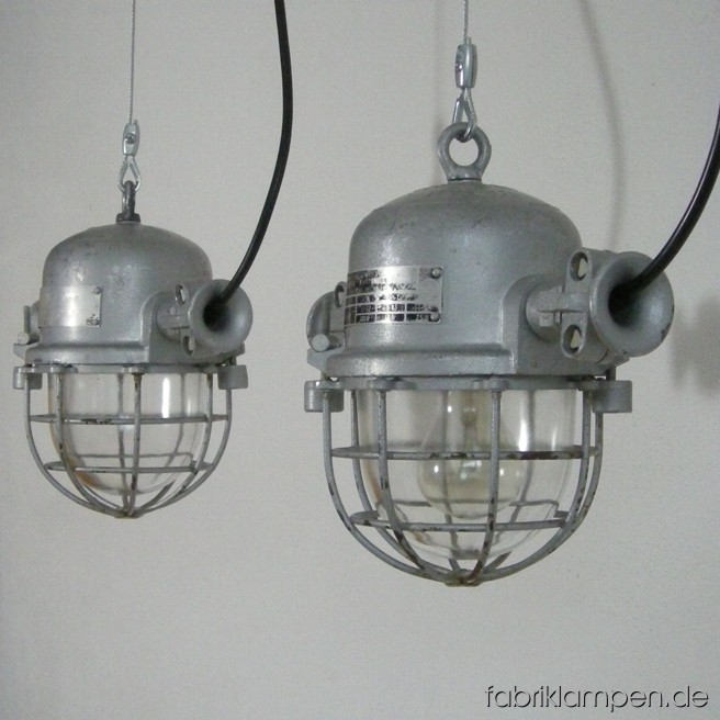 Hübsche kleine Industrielampe (Bunkerlampe) mit Aluminiumgehäuse, Stahlgitter und Schutzglas. 80 Stück vorhanden. Die Lampen sind gereinigt, neu elektrifiziert (ausgestattet mit ca. 2 m Kabel) und getestet. Gesamthöhe: ca. 26 cm, Durchmesser ohne Ohren ca. 18 cm. Auch in längerer Version auf Lager.