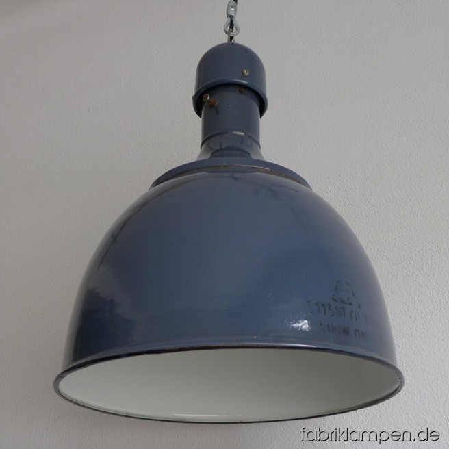 Zierliche blaue Industrielampe mit Aufschrift. Seltene Form mit schlankem Hals. Material: blau (hellblau, mit etwas grau) emaillertes Blech. Die Lampe ist perfekt erhalten, gereinigt, neu elektrifiziert und mit Drahtseil-Aufhängung ausgestattet. Sie hat eine E27-Porzellanfassung und ist daher mit allen gängligen Leuchtmitteln einsatzbar (incl. LED- und Energiespar-Birnen). Höhe ca. 46 cm, Durchmesser ca. 36 cm.