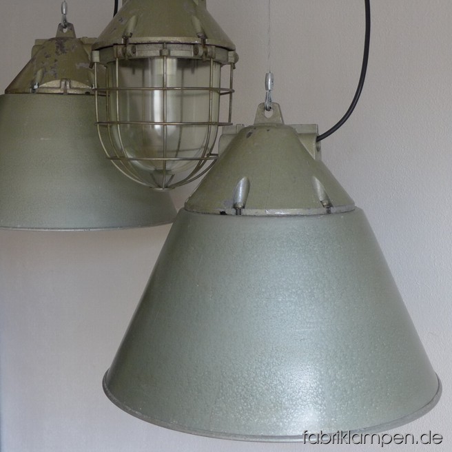 Die ultimativen 3 in 1 Lampen: ob Bunkerlampe mit oder ohne Schirm oder eine einfache Lampe (ohne Schutzgitter und -Glas) – mit diesen Industrieleuchten aus Aluminium können Sie alle drei haben. Die Lampen lassen sich mit 6 Schrauben aufzumachen bzw. umbauen. Diese Lampen mit grünem Hammerschlaglack (Schirm innen mit weisser Farbe) haben eine schöne Patina, sind gereinigt und neu elektrifiziert. Sie haben neue E27-Porzellanfassungen und sind mit allen gängigen Leuchtmitteln (incl. LED- und Energiespar-Birnen) einsatzbar. Höhe der Lampen mit Schirm ca. 45 cm (als Bunkerlampe 44,5 cm), Durchmesser Schirm ca. 55 cm.