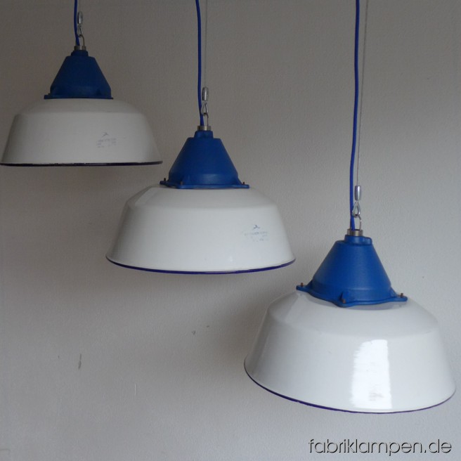 Große  weisse Industrielampen mit blauen gusseisernen Oberteilen. Material: weiss emaillertes Blech mit blauer Umrandung unten (selten), gusseisernes Oberteil (blau lackiert). Die Lampen haben die Spuren der vergangenen Jarhzehnten (Verfärbungen, Abplatzer, Roststellen etc., besonders an Rändern und bei den Schraubenlöchern in den Schirmen) wie es auch sein soll. Sie sind gereinigt, neu elektrifiziert und mit Drahtseil-Aufhängung ausgestattet. Die Lampen haben E27-Fassungen und sind mit allen gängigen Leuchtmitteln einsatzbar (incl. LED- und Energiespar-Birnen). Alle Lampen werden mit 2 Meter blauem Textilkabel geliefert, andere Längen sind auch möglich. Die Maßen: Durchmesser ca. 41 cm, Höhe ca. 28 cm (ohne Aufhängeöse). Die Lampen können auf Wunsch auch mit Stahlrohr-Aufhängung und Baldachin geliefert werden (gegen Aufpreis). Andere RAL-Farben mit passendem Textilkabel sind auch möglich (s. letztes Bild unten, hier mit der kleineren Version dieser Lampen – Durchmesser 36 cm).