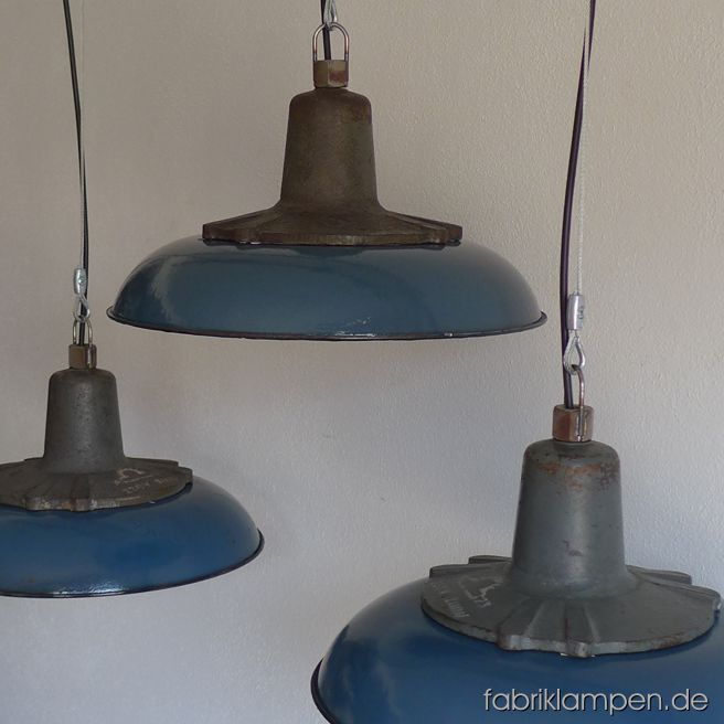 Sehr schöne blaue Industrieleuchten mit gusseisernen Oberteilen und blauen  Emailleschirmen. Aktuell haben wir über 30 Exemplare auf Lager. Die Lampen haben die Spuren der vergangenen Jarhzehnten, sie sind gereinigt und neu elektrifiziert, ausgestattet mit neuen E27 Fassungen. Sie bekommen die Lampen mit 2 Meter Kabel und massiven Aufhängeösen für die sichere Aufhängung (Aufhängung wird nicht mitgeliefert). Material: blau (innen weiß) emailliertes Blech, gusseisernes Oberteil. Gegen Aufpreis können die Lampen auch mit Stahlrohr-Aufhängung und Baldachin geliefert werden. Höhe der Lampen 20 cm, Durchmesser Schirm 41 cm.