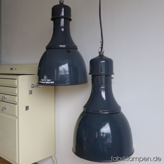 Sehr große graublaue Industrielampe mit Aufschrift – in dieser Form und Größe eher selten. Die Lampen haben die starken Spuren der vergangenen Jarhzehnten (Abplatzer, Roststellen: alle von uns behandelt), sie sind gereinigt und neu elektrifiziert (E27). Material: blaugrau emailliertes Stahlblech. Höhe der Lampen ca. 64 cm, Durchmesser ca. 41 cm.