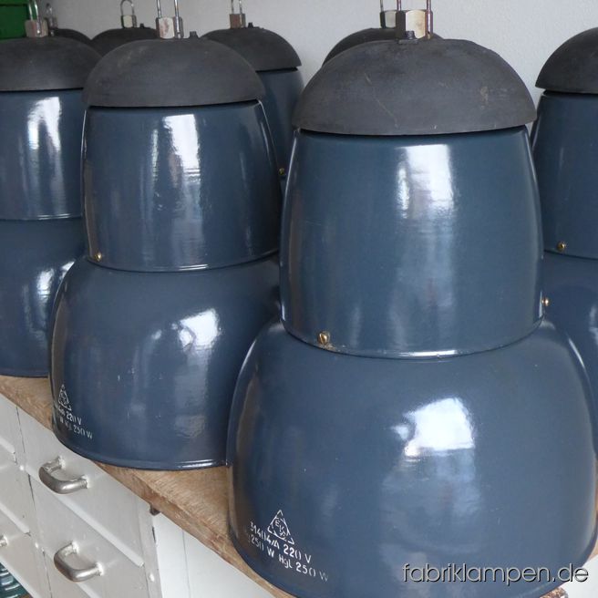 Kompakte alte graublaue Emaille Lampe mit gusseisernem Deckel. Sie hingen in einer alten Textilfabrik, wir haben 35 Exemplare auf Lager. Die Lampen sind gut erhalten und haben nur geringe Spuren der vergangenen Jarhzehnten (kleine  Abplatzer, Roststellen and Co. – wir haben die alle behandelt). Sie sind gereinigt und neu elektrifiziert (E27). Material: graublau emailliertes Stahlblech, Gusseisen. Höhe der Lampen ca. 50 cm (ohne Öse), Durchmesser ca. 41 cm, Gewicht ca. 7 kg. Die Lampen werden mit 2 Meter Kabel geliefert (andere Längen sind natürlich möglich). Wir haben diese Lampen auch in schwarz, die größere Version (Durchmesser 51 cm) ist auch auf Lager, sogar einige mit Schutzglas sind auch da – für Details & Preise dieser Ausführungen sprechen Sie uns einfach an.