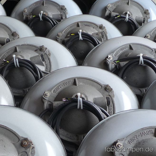 Group of casted iron lamps with safety glasses and grids & pale gray enameled shades.