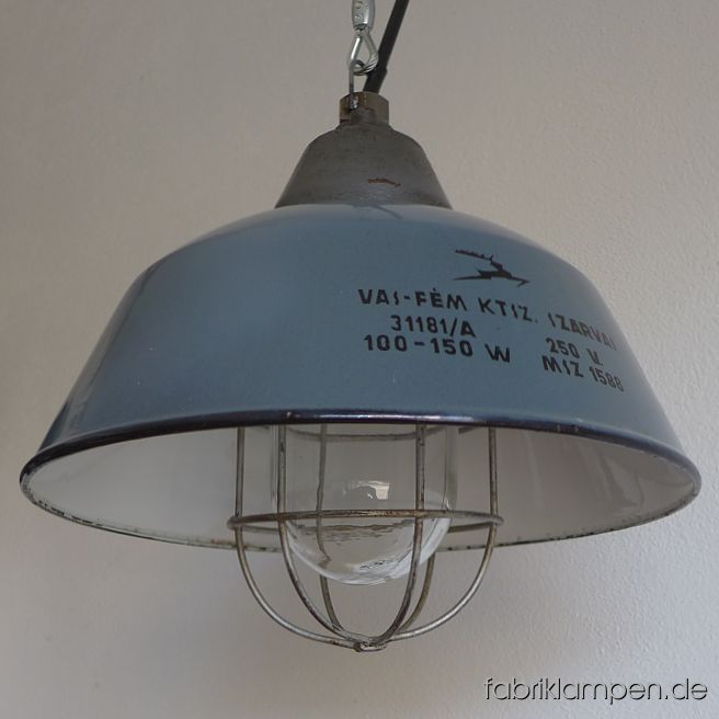 Alte graue Industrielampe mit Schutzglas, Gitter und grauem Emailleschirm. Die Beschriftung mit Hirsch ist die Größte unter den verschiedenen Ausführungen dieses Types. Aktuell haben wir 20 Exemplare auf Lager, darunter auch einige andere Farbvariante, wie graublau, blau. Die Lampen haben die Spuren der vergangenen Jarhzehnten (kleine  Abplatzer, Roststellen, Kratzer, Verfärbungen and Co. – wir haben die alle behandelt). Sie sind gereinigt und neu elektrifiziert, ausgestattet mit neuen E27 Porzellanfassungen. Material: grau (innen weiß) emailliertes Blech, gusseisernes Oberteil, Stahlgitter, Schutzglas. Die Lampen werden mit 2 meter Kabel (andere Länge ist natürlich möglich), mit Aufhängeöse, ohne Aufhängung geliefert. Höhe der Lampen 30,5 cm, Durchmesser Schirm 36 cm.