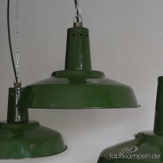 Alte grüne Industrielampen mit Herstellermarke. Die Lampen haben die deutlichen Spuren der vergangenen Jahrzehnte (Abplatzer, Roststellen, Kratzer, Verfärbungen and Co.). Sie sind gereinigt und neu elektrifiziert (E27 Keramikfassung). Material: grün (innen weiß) emailliertes Stahlblech. Im oberen Halsbereich mit Löchern (für Lüftung/Kühlung), innen mit Halterung für Gläser. Die Lampen werden ohne Gläser geliefert – sie waren früher auch ohne Gläser im Gebrauch. Die Leuchten sind ziemlich groß, trotzdem nicht klobig, da der Schirm selbst nicht sehr hoch ist. Die Lampen werden mit Aufhängeöse und 2 Meter Kabel geliefert (andere Längen sind natürlich möglich), auf Wunsch können sie auch mit Textilkabel und Ketten- oder Stahlrohr-Aufhängung ausgestattet werden (gegen Aufpreis). Durchmesser 46 cm, Höhe 30 cm. Wir haben auch die kleinere Variante auf Lager: Durchmesser 39 cm, Höhe 24 cm.
