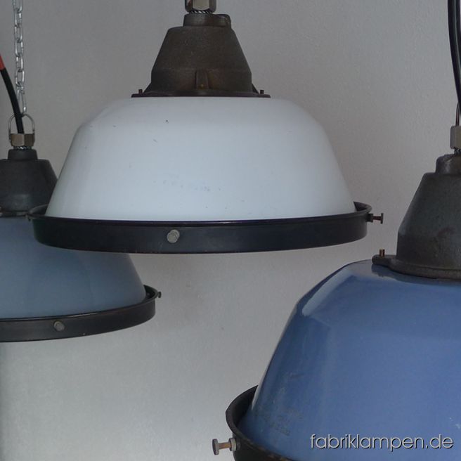 Alte Emaillelampen mit Schutzgitter und Glas. Wir haben diese Lampen in drei Hauptfarben (grau, blau, weiss) und in einigen Durchgangs-Farbtönen (Varianten in graublau und blaugrau) auf Lager. Die Lampen haben geringe Spuren der vergangenen Jahrzehnte (Abplatzer, Kratzer, Verfärbungen and Co.), die Gitter weisen teilweise stärkere Altersspuren auf. Die Leuchten sind gereinigt und neu elektrifiziert (mit E27 Keramikfassung). Material: gusseisernes Oberteil, grau/blau/weiss (innen weiß) emailliertes Schirm aus Stahlblech, Schutzgitter und Schutzglas. 
Die Lampen werden mit Aufhängeöse und 2 Meter Kabel geliefert (andere Längen sind natürlich möglich), auf Wunsch können sie mit Ketten-oder Stahlrohr-Aufhängung ausgestattet werden (gegen Aufpreis). Durchmesser Lampe 36 cm, Höhe 23 cm, Durchmesser mit Schutzgitter 37 cm.