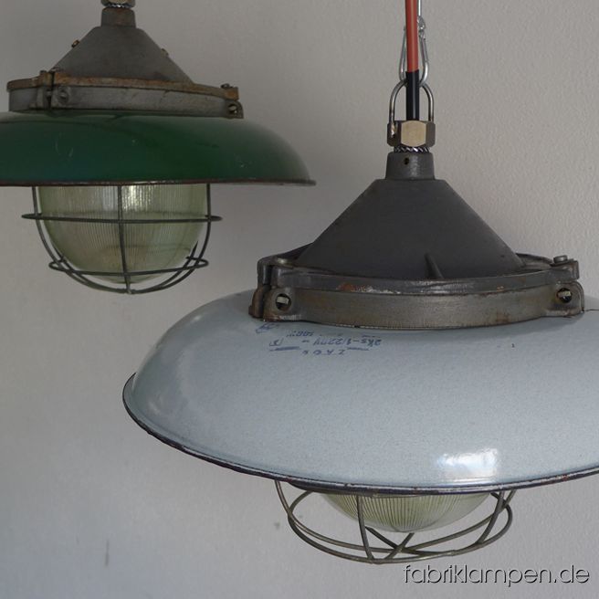 Alte grüne und hellgraue Industrielampen mit Emailleschirm. Die Lampen haben die deutlichen Spuren der vergangenen Jahrzehnte (Abplatzer, Roststellen, Kratzer, Verfärbungen and Co.). Sie sind gereinigt und neu elektrifiziert (E27 Keramikfassung). Material: guseisernes Oberteil, grün oder hellgrau (innen weiß) emailliertes Stahlblech, Schutzglas und Schutzgitter. Die Lampen werden mit Aufhängeöse und 2 Meter Kabel geliefert (andere Längen sind natürlich möglich), auf Wunsch können sie auch mit Textilkabel und Ketten- oder Stahlrohr-Aufhängung ausgestattet werden (gegen Aufpreis). Durchmesser ca. 41 cm, Höhe ca. 30 cm.