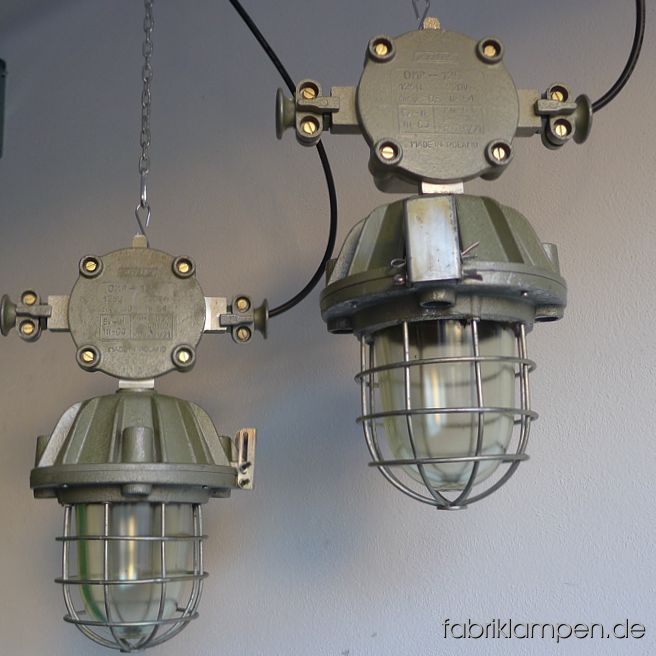 Alte, seltene Bunkerlampe mit robuster Verteilerdose und Ohren (Kabelausführungen). Die Leuchten haben einen seltenen hellgrünen Farbton. Die Lampen haben geringe Spuren der vergangenen Jahrzehnte (Abplatzer, Kratzer, Verfärbungen and Co.), die Gitter weisen teilweise stärkere Altersspuren auf. Die hammerschlaggrüne Beschichtung ist teilweise abgerieben. Die Leuchten sind gereinigt und neu elektrifiziert (mit E27 Fassung). Material: Aluminium Oberteil, Schutzgitter aus Stahl, Schutzglas (Thermoglas). Diese IndustrielLampen werden mit Aufhängeöse und 2 Meter Kabel geliefert (andere Längen sind natürlich möglich), auf Wunsch können sie mit Ketten-Aufhängung ausgestattet werden (gegen Aufpreis). Durchmesser Lampe mit Ohren 33 cm, Höhe 53 cm. Wegen der stattlichen Höhe, des Gewichtes und der Erscheinung sind diese robusten Industrielampen in erster Linie für größere Räume zu empfehlen. Fassung: Porzellanfassung E27, geeignet für alle gängigen Leuchtmittel (LED-, Energiespar-, Halogen- und Glühbirnen): Halogen- und Glühbirnen sind bis maximal 60 Watt Leistung verwendbar. Unsere Empfehlung für diese geschlossenen Lampen sind – wie immer - die LED-Leuchtmittel (zum Beispiel in Kohlefadenoptik). Die Leuchten werden ohne Leuchtmittel geliefert. Verkabelung: neu elektrifiziert, mit Qualitätskabel made in Germany, Länge 2 Meter. Andere Längen sind natürlich möglich (ggf. gegen Aufpreis). Aufhängung: Die Lampen werden mit Aufhängeöse, ohne Aufhängung geliefert. Bitte sorgen Sie für die geeignete Aufhängung der Lampen - die Leuchten mit Kabel zu heben oder aufzuhängen ist unzulässig. Gegen Aufpreis kann eine Ketten-Aufhängung – verzinkt, 2 Meter, oben und unten mit Karabinern, ohne Baldachin - mitgeliefert werden. Verwendung: Die Leuchten sind ausschließlich für Innenbereich geeignet. Bitte benutzen Sie die geschlossenen Lampen mit LED-Leuchtmitteln. Unsere Prinzipien: Authentizität: diese Lampen, wie alle unserer Lampen, sind originale, alten, gebrauchten Lampen aus der Zeit von etwa 1920 bis in die 1970er Jahre (sehr selten 1980-er Jahre). Die Mehrheit der Leuchten stammt aus den 1950-ern, 1960-ern Jahren. Bei uns finden Sie keine Replikate. Exklusivität: wir verkaufen unsere Lampen, Möbel und Objekte ausschließlich auf fabriklampen.live. Wir sind auf keinen Sammelseiten oder Marktplätzen vertreten.