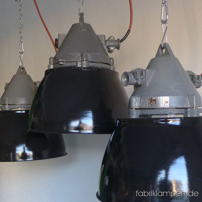 Alte, schwarze Industrielampen mit Emailleschirm und Schutzglas. 

Diese Lampe besteht aus einem konischen Oberteil mit Schutzglas und einem Emailleschirm. Zwischen Oberteil und Emailleschirm gibt es konstruktionsbedingt eine Spalte. 

Die Lampen haben geringe Spuren der vergangenen Jahrzehnte (Abplatzer, Kratzer, Verfärbungen, moderate Oxidation- bzw. Roststellen, and Co.). Die graue Beschichtung des Oberteils ist teilweise abgerieben. 

Die Leuchten sind gereinigt und neu elektrifiziert (mit E27 Fassung). Material: Aluminium Oberteil, aussen schwarz, innen weiss emeilliertes Stahlblech, Schutzglas (Thermoglas). 

Die Lampen werden mit Aufhängeöse und 2 Meter Kabel geliefert (andere Längen sind natürlich möglich), auf Wunsch können sie mit Ketten-Aufhängung ausgestattet werden (gegen Aufpreis). 

Die Abmessungen: Durchmesser Lampe (Schirm) 39 cm, Höhe 44 cm. 

Wegen der Höhe, des Gewichtes und der Erscheinung können wir diese robusten Industrielampen in erster Linie für höhere Räume (bzw. über Tische oder Theken & Tresen) empfehlen. 
Technische Details:

Fassung: Porzellanfassung E27, geeignet für alle gängigen Leuchtmittel (LED-, Energiespar-, Halogen- und Glühbirnen): Halogen- und Glühbirnen sind bis maximal 60 Watt Leistung verwendbar. Unsere Empfehlung für diese geschlossenen Lampen sind – wie immer - die LED-Leuchtmittel (zum Beispiel in Kohlefadenoptik). Die Leuchten werden ohne Leuchtmittel geliefert.

Verkabelung: neu elektrifiziert, mit Qualitätskabel made in Germany, Länge 2 Meter. Andere Längen sind natürlich möglich (ggf. gegen Aufpreis). 

Aufhängung: Die Lampen werden mit Aufhängeöse, ohne Aufhängung geliefert. Bitte sorgen Sie für die geeignete Aufhängung der Lampen - die Leuchten mit Kabel zu heben oder aufzuhängen ist unzulässig. Gegen Aufpreis kann eine Ketten-Aufhängung – verzinkt, 2 Meter, oben und unten mit Karabinern, ohne Baldachin - mitgeliefert werden.

Verwendung: Die Leuchten sind ausschließlich für den Innenbereich geeignet. Bitte benutzen Sie die geschlossenen Lampen mit LED-Leuchtmitteln.

Unsere Prinzipien: 

Authentizität: diese Lampen, wie alle unserer Lampen, sind originale, alten, gebrauchten Lampen aus der Zeit von etwa 1920 bis in die 1970-er Jahre (sehr selten 1980-er Jahre). Die Mehrheit der Leuchten stammt aus den 1950-ern, 1960-ern Jahren. Bei uns finden Sie keine Replikate. 

Exklusivität: wir verkaufen unsere Lampen, Möbel und Objekte ausschließlich auf fabriklampen.live. Wir sind auf keinen Sammelseiten oder Marktplätzen vertreten. 

