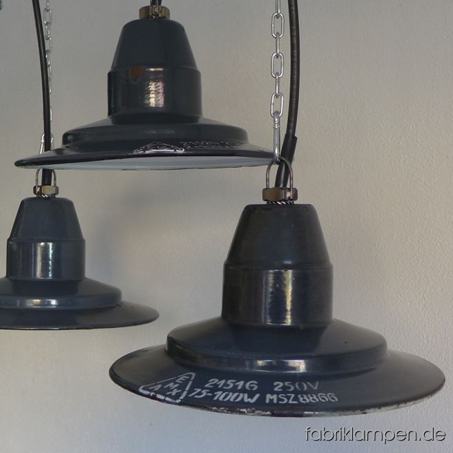 Kleine Emaille Fabriklampen mit Aufschrift aus verschiedenen Epochen eines Herstellers (EKA, später EMAX, von den 1940ern Jahren bis Ende 1950ern Jahren). Seltene, niedrige, elegante Form . Material: außen graublau (selten schwarz), innen weiß emailliertes Stahlblech mit Aufschrift (in weiß oder in schwarz) . Die Lampen haben die üblichen, teilweise starken Spuren der vergangenen Jahrzehnte (Abplatzer, Kratzer, Verfärbungen, kleinere Roststellen, und Co.). Wir haben diese alle behandelt. Die Leuchten sind gereinigt und neu elektrifiziert (mit E27 Porzellanfassung). Höhe der Lampe ca. 15 cm, Durchmesser ca. 30,5 cm. Die Lampen werden mit Aufhängeöse und 2 Meter Kabel geliefert (andere Längen sind natürlich möglich), auf Wunsch können sie mit Textilkabel, Ketten- oder Stahlrohr-Aufhängung ausgestattet werden (gegen Aufpreis).