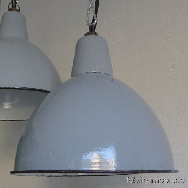 Alte hellgraue Emaillelampe mittlerer Größe, seltene Form. Die Lampen haben die üblichen Spuren der vergangenen Jahrzehnte (Abplatzer, Roststellen, Kratzer, Verfärbungen und Co.). Sie sind gereinigt und neu elektrifiziert (E27 Keramikfassung). Material: hellgrau (innen weiß) emailliertes Stahlblech. Die Lampen werden mit Aufhängeöse und 2 Meter Kabel geliefert (andere Längen sind natürlich möglich), auf Wunsch können sie auch mit Textilkabel und Ketten- oder Stahlrohr-Aufhängung ausgestattet werden (gegen Aufpreis). Die Abmessungen: Durchmesser Lampe (Schirm) 31 cm, Höhe 23 cm. 