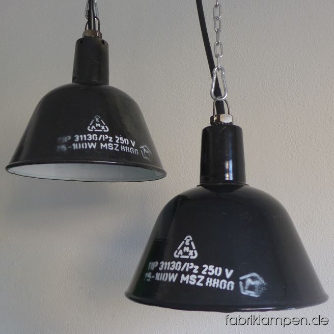 Kleine schwarze Emaille Fabriklampe mit weißer Aufschrift. Seltene, hohe Form mit schlankem Hals. Material: schwarz (innen weiß) emailliertes Stahlblech. Die Lampen haben die üblichen Spuren der vergangenen Jahrzehnte (Abplatzer, Kratzer, Verfärbungen, kleinere Roststellen, und Co.). Wir haben diese alle behandelt. Die Leuchten sind gereinigt und neu elektrifiziert (mit E27 Porzellanfassung). Höhe der Lampe ca. 23 cm, Durchmesser ca. 26 cm. 
Die Lampen werden mit Aufhängeöse und 2 Meter Kabel geliefert (andere Längen sind natürlich möglich), auf Wunsch können sie mit Textilkabel, Ketten- oder Stahlrohr-Aufhängung ausgestattet werden (gegen Aufpreis). 
Auch in graublau auf Lager.
 