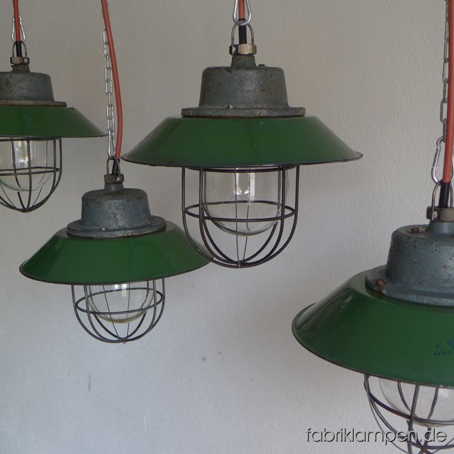 Alte kleine Industrielampe mit Emailleschirm in grün. Es handelt sich hier um die kleinere Variante dieser Lampen. Material: gusseisernes Gehäuse, grün (innen weiß) emailliertes Stahlblech (teilweise mit Herstellermarke), Schutzglas und Schutzgitter. Die grüne Emaille hat verschiedene Farbtöne, bis pastellgrün. Diese schönen Fabriklampen haben die üblichen Spuren der vergangenen Jahrzehnte (Abplatzer, Roststellen, Kratzer, Verfärbungen und Co.). Sie sind gereinigt und neu elektrifiziert, mit E27 Keramikfassung. Die Fabriklampen werden mit Aufhängeöse und 2 Meter Kabel geliefert (andere Längen sind natürlich möglich), auf Wunsch können sie auch mit Ketten- oder Stahlrohr-Aufhängung ausgestattet werden (gegen Aufpreis). Die Abmessungen: Durchmesser Lampe (Schirm) 30 cm, Höhe ohne Aufhängung lediglich 24 cm.
