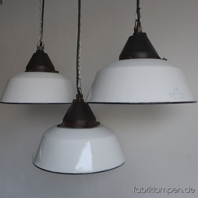 Alte weiße Emaille Fabriklampen mit gusseisernem Oberteil, mit Herstellermarke. Die Lampen haben die Spuren der vergangenen Jahrzehnte (kleine Abplatzer, Roststellen, Kratzer, Verfärbungen und Co. – wir haben die alle behandelt), sie sind gereinigt und neu elektrifiziert, ausgestattet mit neuen E27 Keramikfassungen. Material: weiß emailliertes Stahlblech, gusseisernes Oberteil. Sie bekommen die Lampen mit 2 Meter Kabel (andere Längen oder Textilkabel sind natürlich möglich) und massiven Aufhängeösen für die sichere Aufhängung. Gegen Aufpreis können die Lampen auch mit Ketten-Aufhängung oder Stahlrohr-Aufhängung und Baldachin geliefert werden. Die Abmessungen: Durchmesser Lampe (Schirm) 41 cm, Höhe 28 cm. 