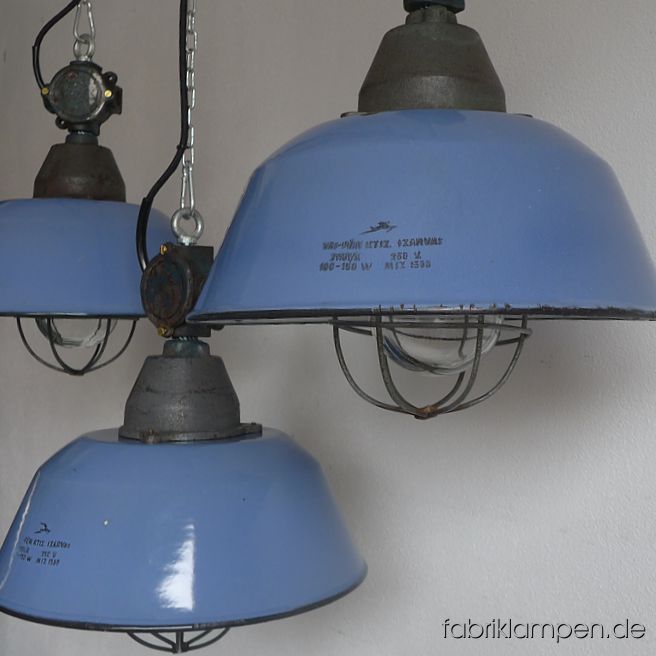 Alte hellblaue Emaille Fabriklampen mit gusseisernem Oberteil und Verteilerdose. Emailleschirm im seltenen blauen Farbton mit Herstellermarke, die Lampe ist mit Glas & Gitter ausgestattet. Die Lampen haben die Spuren der vergangenen Jahrzehnte (Abplatzer, Roststellen, Kratzer, Verfärbungen and Co. – wir haben die alle behandelt), sie sind gereinigt und neu elektrifiziert, ausgestattet mit neuen E27 Keramikfassungen. Material: hellblau emailliertes Stahlblech, gusseisernes Oberteil und Verteilerdose, Glas und Stahlgitter. Sie bekommen die Lampen mit 2 Meter Kabel und massiven Aufhängeösen für die sichere Aufhängung. Gegen Aufpreis können die Lampen auch mit Ketten-Aufhängung geliefert werden. Die Abmessungen: Durchmesser Lampe (Schirm) 36 cm, Höhe 41 cm. 