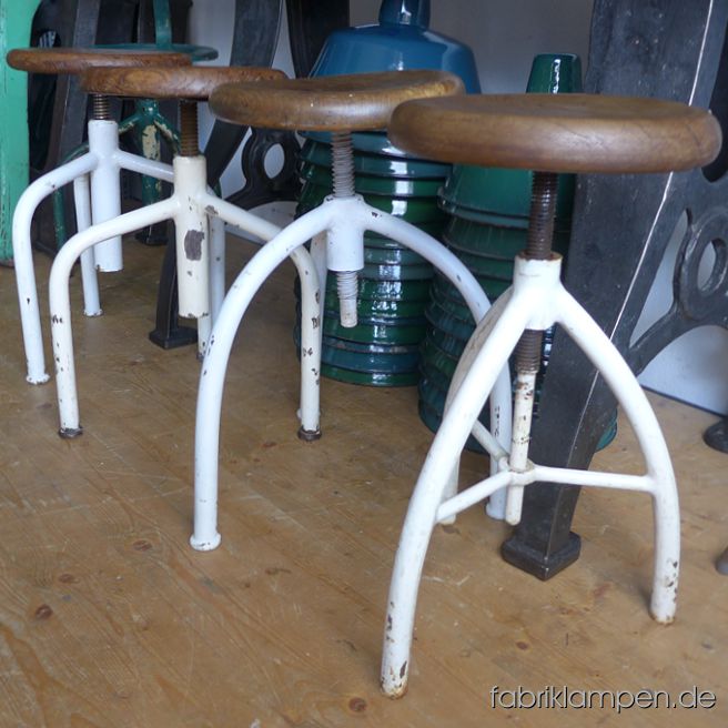 Alter Arzthocker, Hocker, Drehhocker, oder Dreibein. Höhenverstellbar,  mit originalen Sitzflächen aus einem Stück Hartholz. Mehrere Exemplare auf Lager. Die weiss lackierten Gestelle sind gereinigt und konserviert worden. Die originalen alten Sitze sind meist aus Eiche (einmal aus einem anderen Hartholz, s. Bilder) – wir haben diese mit Naturwachs behandelt. Die Sitzplatten (teilweise mit kleinen Rissen am Rand, manchmal mit Gebrauchsspuren bzw. Deformationen) sind im Schnitt 5 cm stark und haben eine angenehme Sitzmulde. Der Durchmesser des Sitzes beträgt ca. 30 cm. Massive, unverwüstliche Ausführung, geeignet für Gastronomie oder Ihre Loft-Küche. Die Spindeln & Gewinden sind im guten Zustand. Sitzhöhe: zwischen 49 und 64 cm.  