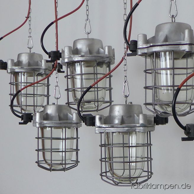 Alte Fabriklampe Bunkerlampe aus Aluminium mit Schutzglas und Gitter. Die Lampen sind aufgearbeitet, wir haben diesen Typ auch im Originalzustand auf Lager. Die Lampen sind gereinigt, aufgearbeitet (Gehäuse und Gitter geschliffen), konserviert und neu elektrifiziert. Material: Gehäuse aus Aluminium, Schutzgitter aus Stahl, Schutzglas (Thermoglas). Die Abmessungen: Höhe der Lampen (ohne Aufhängeöse) 30 cm, Durchmesser (ohne „Ohren“) 20 cm. Die Fabriklampen werden mit Aufhängeöse und 2 Meter Kabel geliefert (andere Längen sind natürlich möglich), auf Wunsch können sie mit Ketten-Aufhängung ausgestattet werden (gegen Aufpreis). 