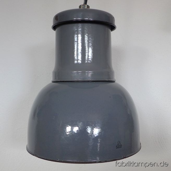 Alte AEG Fabriklampe mit Herstellermarke. Klassische dreiteilige Ausführung, wo alle Teile – gewollt – verschiedene Farbtöne haben. Alte Qualität, dicke Emailleschicht. Diese schöne Fabriklampe hat die Spuren der vergangenen Jahrzehnte (Abplatzer, Roststellen, Kratzer, Verfärbungen und Co.) -  in erster Reihe innen an der Öffnung der Fassung und unten am Rand des Schirmes. Sie ist gereinigt und neu elektrifiziert, mit E27 Keramikfassung. Material: grau (innen weiss) emailliertes Stahlblech. Die Abmessungen: Höhe der Lampe ca. 42 cm, Durchmesser ca. 38 cm. Die Fabriklampe wird mit Aufhängeöse und 2 Meter Kabel geliefert (andere Längen sind natürlich möglich), auf Wunsch kann sie auch mit Textilkabel und Ketten- oder Stahlrohr-Aufhängung ausgestattet werden (gegen Aufpreis). 