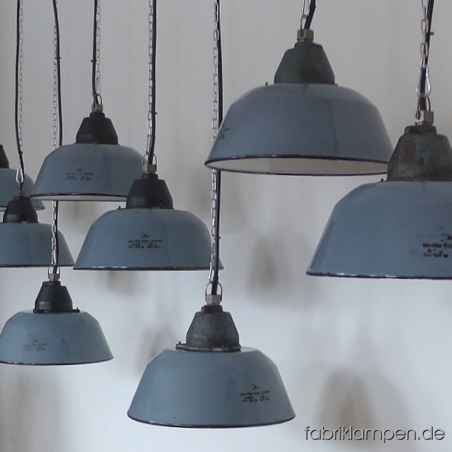 Alte Fabriklampen. Graublaue Emaille Industrielampen mit gusseisernem Oberteil, mit Herstellermarke. Die Farbe ist graublau/blaugrau (hell). Wir haben diese Lampen auch in Richtung grau bzw. blau auf Lager. Die Lampen haben die Spuren der vergangenen Jahrzehnte (Abplatzer, Roststellen, Kratzer, Verfärbungen und Co. – wir haben die alle behandelt), sie sind gereinigt und neu elektrifiziert, ausgestattet mit neuen E27 Keramikfassungen. Material: graublau emailliertes Stahlblech, gusseisernes Oberteil. Sie bekommen die Lampen mit 2 Meter Kabel (andere Längen oder Textilkabel sind natürlich möglich) und massiven Aufhängeösen für die sichere Aufhängung. Gegen Aufpreis können die Lampen auch mit Ketten-Aufhängung oder Stahlrohr-Aufhängung und Baldachin geliefert werden. Die Abmessungen: Durchmesser Lampe (Schirm) 36 cm, Höhe 23 cm. 