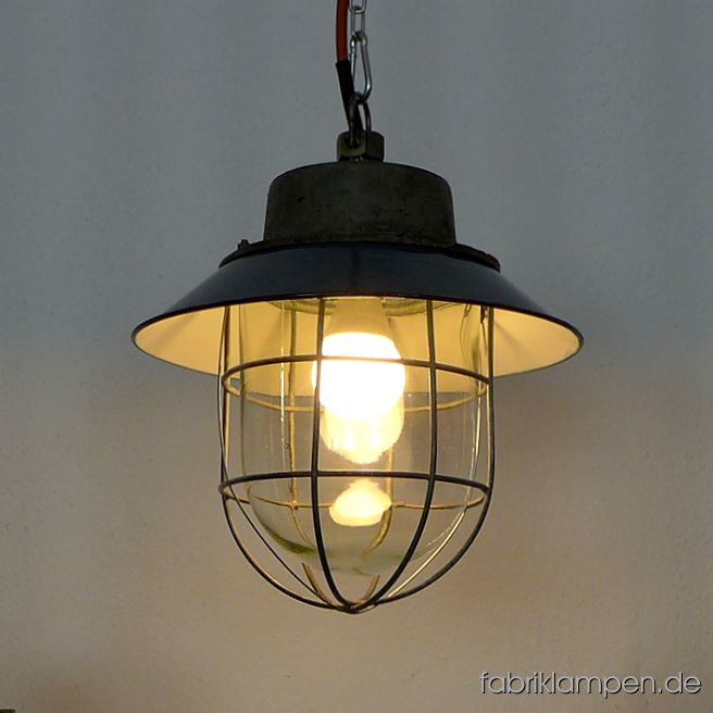Blaue Industrielampe - alte restaurierte Fabriklampe mit Emailleschirm in blau. Material: gusseisernes Gehäuse, blau (innen weiß) emailliertes Stahlblech (mit Herstellermarke), Schutzglas und Schutzgitter. Diese schönen Fabriklampen haben die üblichen Spuren der vergangenen Jahrzehnte (Abplatzer, Roststellen, Kratzer, Verfärbungen und Co.). Sie sind gereinigt und neu elektrifiziert, mit E27 Keramikfassung. Die Fabriklampen werden mit Aufhängeöse und 2 Meter Kabel geliefert (andere Längen sind natürlich möglich), auf Wunsch können sie auch mit Ketten- oder Stahlrohr-Aufhängung ausgestattet werden (gegen Aufpreis). Die Abmessungen: Durchmesser Lampe (Schirm) 30 cm, Höhe ohne Aufhängung 30 cm. 