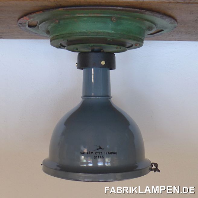 Alte Kranlampe: wir haben 2 alte Kranlampen gefunden. Die seltenen Emaille Lampen waren damals an einem Hallenkran befestigt. Der Aufbau der Lampe ist dementsprechend speziell: eine große, mehrteilige Grundplatte sorgte für die massive Befestigung, eine eingebaute Gummiplatte gewährleistete die nötige Flexibilität beim Einsatz am Kran. 

Seltene Vögel, als Paar schwer zu finden. 

Die Emailleschirme haben (in erster Linie bei den Befestigungspunkten des Gitters) Alters- und Gebrauchsspuren, wie kleine Deformationen, Abplatzer, Roststellen, Kratzer, Verfärbungen. Alles ist, wie immer, gereinigt und konserviert. 

Die Lampen sind neu elektrifiziert, mit E27 Keramikfassung.

Material: eiserne Grundplatte in Originalfarbe, Oberteil Gusseisen, Lampenschirm aus graublauem (innen weiss emailliertem) Stahlblech, Schutzgitter (Stahl) und Schutzglas. 

Die Abmessungen: Höhe der Lampe ca. 47 cm, Durchmesser Grundplatte ca. 51 cm, Durchmesser Schirm ca. 36,5 cm. Das Gewicht beträgt stolze 20 Kg. 

Die Kranlampen werden mit 2 Meter Kabel, ohne Befestigungsmaterial für Ihre Decke geliefert (es ist immer individuell). Kabelführung auf Wunsch durch die Grundplatte (oben) oder durch den gusseisernen Teil der Lampe. Andere Kabellängen sind natürlich möglich. 