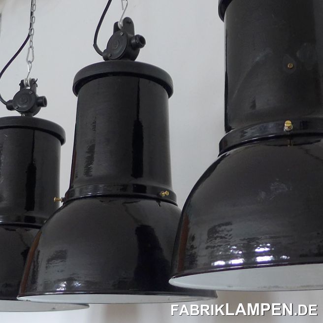 Alte schwarze Industrielampe, sehr selten. Klassische dreiteilige Ausführung, mit gusseisernem Oberteil und Verteilerdose (mit Herstellermarke). Diese seltene Fabriklampe hat die Spuren der vergangenen Jahrzehnte (kleine Dellen, Abplatzer, Roststellen, Kratzer, Verfärbungen und Co.). Sie ist gereinigt, konserviert und neu elektrifiziert, mit E27 Keramikfassung. Material: schwarz, innen weiss emailliertes Stahlblech, Gusseisen. Die Abmessungen: Höhe der Lampe ca. 58 cm, Durchmesser ca. 36 cm. Die Industrielampe wird mit Aufhängeöse und 2 Meter Textilkabel in Farbe Ihrer Wahl geliefert (andere Längen sind natürlich möglich), auf Wunsch kann sie auch mit Ketten-Aufhängung ausgestattet werden (gegen Aufpreis). 
