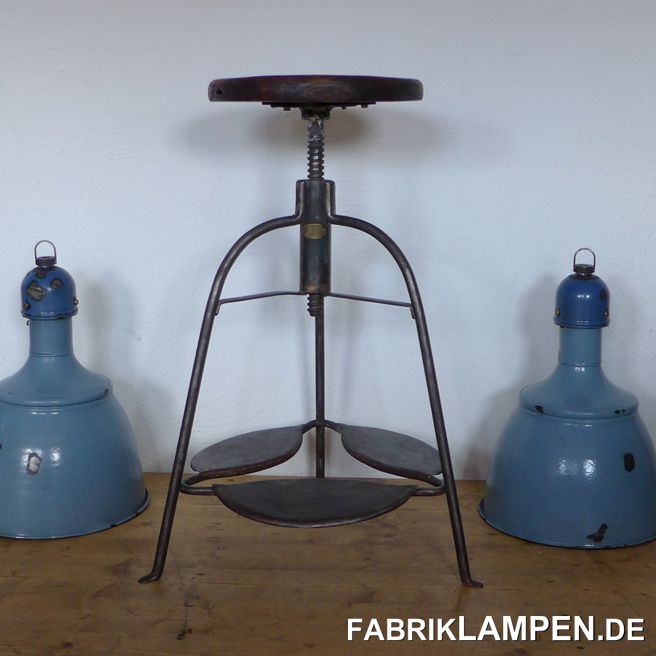 Alter Industriehocker , Werkstatthocker, höhenverstellbarer Drehhocker, Dreibein, mit altem Sitz (Hartholz). Das Gestell ist aufgearbeitet und konserviert. Um ca. 1920, mit Messingplatte des Herstellers. Enorm selten. 

Sehr schöne, interessante Form mit drei großen blattförmigen Fußablagen. In den Fußablagen sind alte Nieten (Kupfer) zu sehen. Sitzplatte aus Hartholz, mit schöner Patina – wir haben sie mit Naturwachs behandelt. Der Durchmesser der Sitzplatte beträgt 35 cm. 

Massive, unverwüstliche Ausführung, geeignet für Gastronomie oder Ihre Loft-Küche. Die Sitzhöhe erlaubt die Nutzung auch bei höheren Tischen/Theken als Barstuhl. 

Die Spindel & das Gewinde sind im guten Zustand. 

Sitzhöhe von 66 bis 84 cm. Durchmesser Sitzplatte 32 cm. 