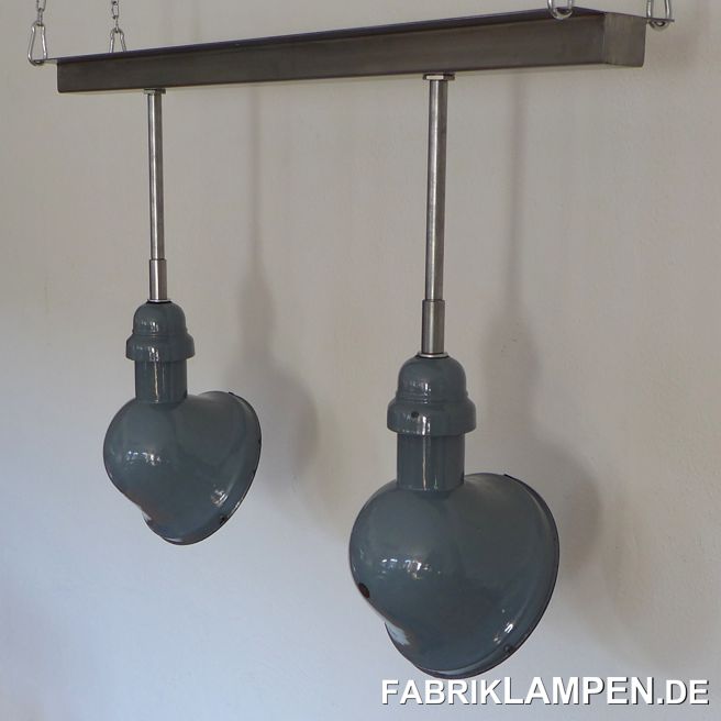 Seltene alte asymmetrische Fabriklampen mit neuer Stahlrohr-Aufhängung und Schiene für die Deckenmontage. 

Alte Emaillelampen mit halbkugelförmigen Schirm und asymmetrischem Hals. 

Diese alten Industrielampen haben die Spuren der vergangenen Jahrzehnte (Kratzer, Abplatzer, Roststellen, Verfärbungen and Co.). Sie sind gereinigt und konserviert. Neu elektrifiziert, mit E27 Keramikfassung. Wir haben diese alten Lampen mit neuen Stahlrohr-Aufhängung und Dose montiert. 

Wegen der asymmetrischen Form sind diese Lampen besonders für Theken, Sideboards oder z. B. für Beleuchtung von Schaufenstern geeignet. 

Material: hellblau (innen weiss) emailliertes Stahlblech, neue Stahlrohr-Aufhängung mit Schiene für die Decke. 

Die Abmessungen: Durchmesser Schirm ca. 22 cm, Breite Schiene 96 cm, Gesamthöhe wie abgebildet ca. 64 cm. Andere Längen für die Aufhängung sind möglich, bitte sprechen Sie uns an! 