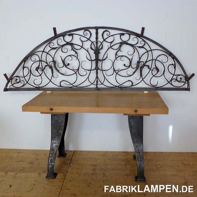 Altes Oberlicht, Schmiedeeisen, Rokoko. Ein Meisterstück aus dem 18. Jahrhundert (ca. um 1780-1800). Mit den typischen Rokoko-Motiven, in der Mitte mit einer eher ungewöhnlichen Darstellung: da ist ein Waldgeist (?) oder Wurzelsepp (?) zu sehen - das Gesicht erinnert mich auch an die früheren sog. Bartmänner. Die ziemlich große Nase deutet eher an einen Wurzelsepp an. 

Die Schmiedearbeit ist hervorragend, damals waren die Meister in der Lage, Eisen nahezu plastisch bearbeiten zu können (und haben dazu nicht nur die Knowhow, sondern auch noch das geeignete Material gehabt). In dem „Spiegel“ gibt es keine klassischen Verbindungen, die verzweigenden Teile sind ineinander „geflochten“. Am Rand sind die Teile mit Nieten zusammengefügt. 

Herkunft: Alpenregion oder Alpenvorland. 
Zustand: konservierter Fundzustand. Wir haben die Oberfläche schonend gereinigt und konserviert. 

Die Breite beträgt 223 cm, die Höhe ist 75 cm (alles am Rand, ohne die Wandhaken gemessen). 

Selbstabholung, Versand auf Anfrage möglich (als Fracht auf Palette). 