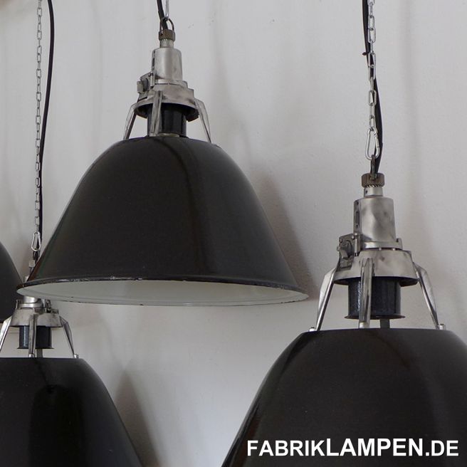 Schwarze Industrielampe, Fabriklampe mit Aluminium Oberteil, aufgearbeitet. 

Gut erhaltene, aufgearbeitete alte Fabriklampen mit speziellem, offenem Kopfteil. Die Industrielampen haben nur minimale Spuren der vergangenen Jahrzehnte (Abplatzer, Roststellen, Kratzer, Verfärbungen und Co.). Sie sind gereinigt und neu elektrifiziert, mit neuen E27 Keramikfassungen. 

Material: schwarz (innen weiss) emailliertes Stahlblech, Aluminium Oberteil. Die schwarze Emaille ist etwas körnig, mit kleinen weissen Pünktchen, auch innen ist die Emaille nicht immer schneeweiss und/oder homogen - Spuren der damaligen Herstellung. Die Kopfteile mit vier Füßen haben wir aufgearbeitet: die alte Farbe entfernt und fein geschliffen – nicht auf Hochglanz poliert, da wir diese etwas rauere Oberfläche für natürlicher halten. 

Sie bekommen die Lampen mit 2 Meter Kabel und massiven Aufhängeösen für die sichere Aufhängung. Gegen Aufpreis können die Lampen auch mit Ketten-Aufhängung geliefert werden. Baldachine können wir auch anbieten. 

Die Abmessungen: Durchmesser Lampe (Schirm) 57 cm, Höhe Schirm 29 cm, Gesamthöhe Lampe (Kopf und Schirm) 51 cm. 
