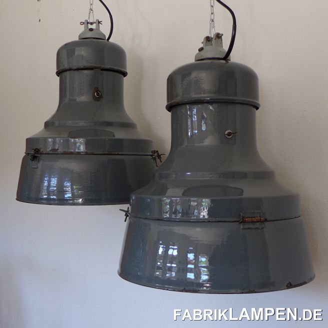 Antike Industrielampen aus den 1930er Jahren. Sehr massive Ausführung, in der Größe sehr selten. Klassische dreiteilige Ausführung, in dieser Form gehören sie zu den größten Lampen. 
Diese seltenen Industrielampen haben die Spuren der vergangenen vielen Jahrzehnte (kleine Dellen, Abplatzer, Roststellen, Kratzer, Verfärbungen und Co.). Eine Lampe ist gut erhalten, die Andere hat sowohl innen als auch außen massive Gebrauchsspuren (wahrscheinlich ist sie irgendwann mal gestürzt). Sie sind gereinigt, konserviert und neu elektrifiziert, mit E40/E27 Keramikfassung (Adapter).
Material: graublau, innen weiss emailliertes Stahlblech, Messing, Gusseisen. 
Die Abmessungen: Höhe der Lampe ca. 62 cm, Durchmesser ca. 50 cm. Das Gewicht beträgt stolze 10 Kg. 
Die Industrielampen werden mit 2 Meter Textilkabel in Farbe Ihrer Wahl geliefert (andere Längen sind natürlich möglich), auf Wunsch kann sie auch mit Ketten-Aufhängung ausgestattet werden (gegen Aufpreis). 