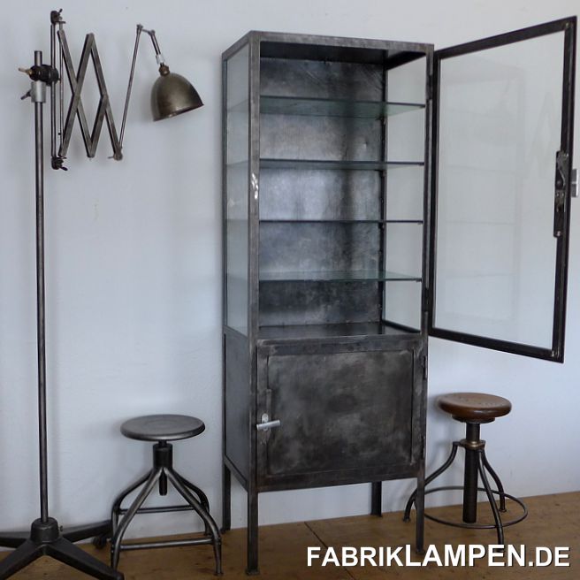 Alter Arztschrank, alte Arztvitrine, restauriert. Wir haben mehrere restaurierte Arztschränke, hier steht ein schmaler Typ mit jeweils einer Tür oben und unten. 
Die alte Farbschicht wurde schonend entfernt, um die unvergleichbare Patina des alten Eisens zu behalten. Anschließend wurde der Schrank mit einer Öl-Wachs-Mischung versiegelt, somit die Oberfläche natürlich und angenehm bleibt. 

Der Schrank hat gute Proportionen: im verglasten Oberteil befinden sich 4 gläserne Regalböden, diese sind noch original: aus 8 mm starkem Glas gefertigt, mit altem Muster und Strukturen. Man kann natürlich auch weniger Regalböden einsetzen, somit auch größere Gegenstände in dem Schrank Platz finden. 

Im unteren Teil des Schranks haben wir den alten Regalboden aus Metall (er war ziemlich abgerockt) durch einem neuen Regalboden aus (altem, recyceltem) Drahtglas ersetzt. 

Material: Stahl, Glas. Bei den Blechteilen kann man noch deutlich sehen, dass diese noch mit den alter Technologie gewalzt sind. Ebenso bei den genieteten und geschweißten Teilen. Wie immer bei uns: nur alt und Original, bei uns finden sie keine Replikate. 

Wir haben auch zweitürige Arztschränke, auch offene Regale, alles aufgearbeitet und wohnfertig. 

Die Abmessungen: Breite 65 cm, Höhe 180 cm, Tiefe 40 cm. 