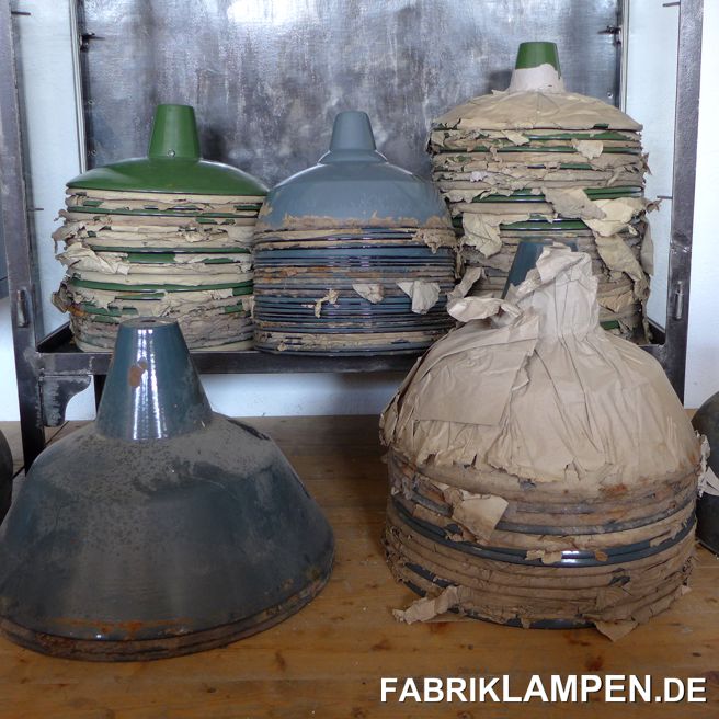 Juli 2020 bei fabriklampen.live. 

Vor kurzem konnten wir alte Fabriklampen (Emaillelampen) aus einem Lagerbestand erworben. So was passiert manchmal, ist aber relativ selten. Ich wollte es auch nicht glauben, als ein Verkäufer mich vor kurzem angeschrieben hat. Allerdings habe ich der Sache eine Chance gegeben und in der Tat: die Lampen – unter anderen eine Menge Schirme aus dem Hause von Louis Poulsen – waren wirklich alte, originale Lampen, noch im alten Papier verpackt. Der Großvater des Verkäufers hat diese vor Jahrzehnten auf dem Dachboden verstaut und das letzte Halbjahrhundert haben die Lampen dort in einem Dornröschenschlaf verbracht. Ich habe sie natürlich sofort gekauft. Es handelt sich hier um einen wirklich alten Posten. In der Regel werden noch Lampen als alten Lagerbeständen aus den 1970-er, 1980-er Jahren gefunden. Diese sind zwar auch seltener geworden, die Sache ist aber nicht unmöglich.

Es gibt auf dem Markt viele Lampen, die als alt verkauft werden: sind sie wirklich alt?

Lampenschirme aus alten Lagerbeständen weisen fast immer Altersspuren auf: kleine Stellen mit Rost, Abplatzer etc., wie hier auf den Bildern zu sehen ist. Die Emaille ist frisch, aber nicht wie bei den Fake-Lampen. Wenn Lampen in größeren Anzahlen seit vielen Jahren in einem tadellosen Zustand verkauft werden (typischerweise auf online Marktplätzen, teilweise aber auch in einzelnen Webshops), noch dazu in Formen, die es nur auf diesen Seiten gibt, meistens auch in mehreren Farben, ist Zweifel angebracht.

Relativ einfache Formen, die sonst nie als Gebrauchtlampe auftauchen, in Farben, die es für die historischen Industrielampen nie gaben (gelb, rosa, elfenbein, etc. pp.) sind in der Regel auch neu. Ich habe mal in einem Webshop mit Industrielampen gesehen, wo der Verkäufer (oder Hersteller) die Emaille mit Hammer abgeschlagen hat, somit die Lampen gebraucht aussehen, und so die neuen Lampen als „alt“ verkauft hat. Das ganze sah natürlich – gelinde gesagt – nicht authentisch aus.
Perfekte Fälschungen?

Viele Lampen werden ganz perfekt gefälscht. Ein typisches Beispiel dafür sind einige osteuropäischen Lampen. Diese werden in verscheidensten Farben neu produziert. Alles ist perfekt, sogar die Herstellermarke in der Emaille. Mit Verteilerdosen und allen Drum und Dran werden die Lampen auch heute produziert und brav als alt verkauft.
Auch die alten EKA/EMAX Lampen werden gefälscht: diese sind aber qualitativ leicht zu erkennen und in der Regel fehlt die Herstellermarke. So nebenbei: hier werden auch Scherenlampen produziert (sowohl für die Decke als auch für die Wand) und als alt vertrieben.
Neben Osteuropa werden die Lampen, die dann als alt verkauft werden, in der Regel in Asien hergestellt.

Die Liste könnte noch weiter fortgesetzt werden, der Schluss ist: Augen auf, wenn Sie alte Lampen suchen!

So nebenbei: auch bei alten Industriemöbeln – da gibt es langsam mehr Replikate (als alt bezeichnet) als Originale… 