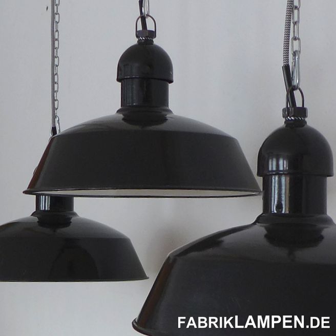 Alte schwarze Industrielampen aus den 1930er Jahren. Vor kurzem haben wir aus dem Dachboden einer alten Fabrik insgesamt 200 Lampen gekauft, ein Teil davon (60 Stück) sind diese Lampen. Auf dem letzten Bild in der Galerie sind die alten Fabriklampen im Fundzustand zu sehen. Die Leuchten haben die klassische zweiteilige Form, die der Lüftung (Kühlung) der Lampen diente. 

Die alten Emaillelampen stammen aus deutscher Herstellung. Besonders bei diesen Industrielampen ist, dass der Kopf oben ein Gewinde hat. Dies ermöglichte die Verwendung eines längeren Gewinderohrs, damit sich die Höhe der Fassung (des Leuchtmittels) stufenlos einstellen lässt. So kann man den Abstrahlwinkel und damit den Lichtkegel einstellen & optimalisieren. Auf Wunsch können wir die Lampen auch in dieser Ausführung liefern. 

Diese schönen Fabriklampen haben die üblichen (teilweise starken) Spuren der vergangenen Jahrzehnte wie Abplatzer, Roststellen, Kratzer, Verfärbungen und Co.. Sie sind restauriert: gereinigt, konserviert und neu elektrifiziert, mit neuen E27 Keramikfassungen.

Material: schwarz (innen weiß) emailliertes Stahlblech. 

Die Abmessungen: Höhe der Lampen ca. 26 cm (ohne Aufhängeöse), Durchmesser ca. 41 cm. 

Die alten Industrielampen werden mit 2 Meter Textilkabel Farbe Ihrer Wahl (andere Längen sind natürlich möglich) und massiver Aufhängeöse für die sichere Aufhängung geliefert. Gegen Aufpreis können die Lampen auch mit Ketten- oder Stahlrohr-Aufhängung geliefert werden. Baldachine können wir auch anbieten. 