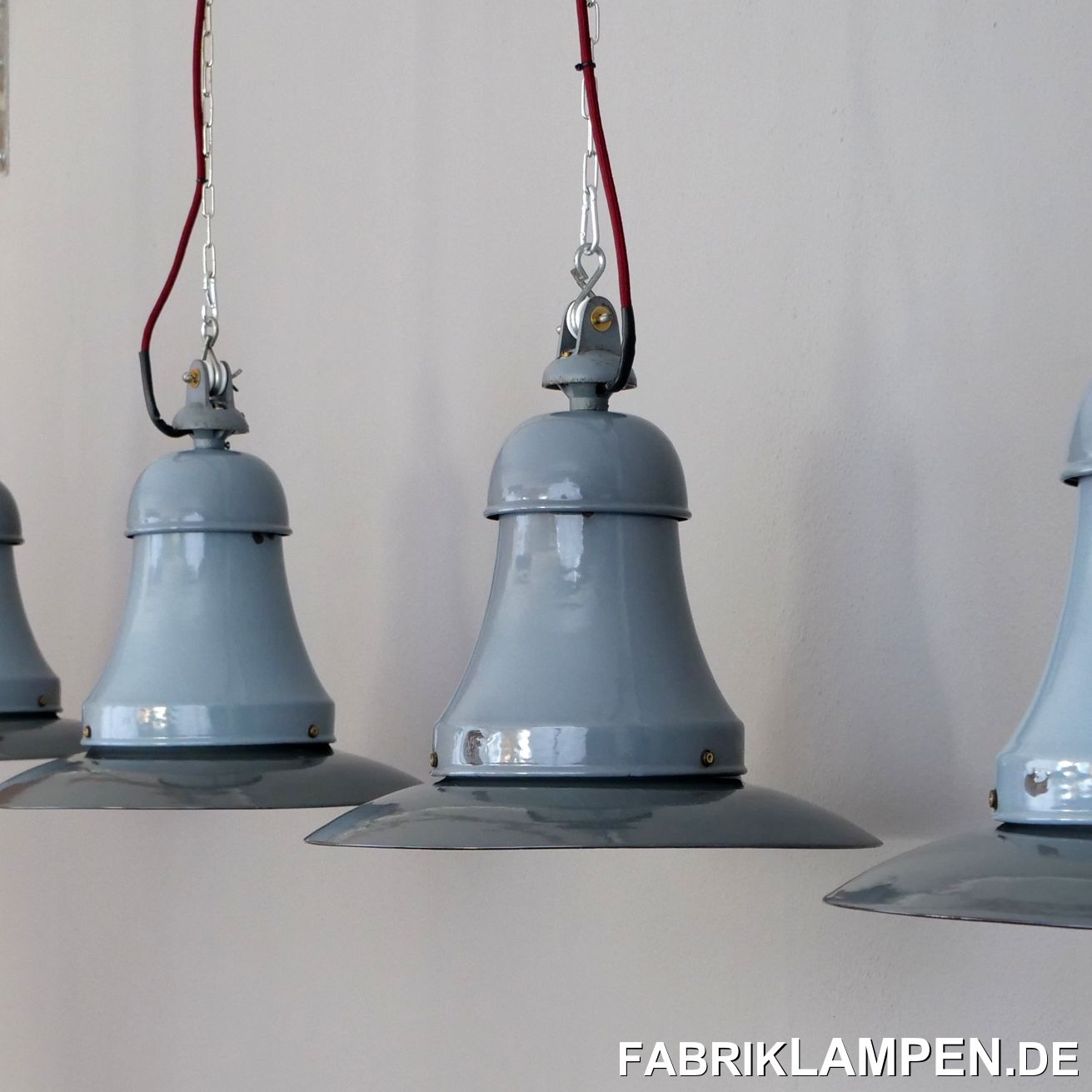  Alte Industrielampen, Fabriklampen mit zwei Fassungen aus dem Hause Siemens. Wir haben vor Kurzem diese Lampen aus einer alten Halle in Hessen gekauft. Die Lampen waren bis zur letzten Minute in der geheizten Halle im Dienst und dementsprechend sind sie für den Alter sehr gut erhalten. Auch die originalen Aufhängungen mit den Porzellanrollen sind vorhanden. Diese Lampen waren in der Regel unter rauen Bedingungen im Einsatz und haben massive Gebrauchsspuren – diese Erhaltung in der Menge ist heutzutage sehr selten zu finden. 

Die Industrielampen haben sehr geringe Spuren der vergangenen Jahrzehnte (Abplatzer, Roststellen, Kratzer, Verfärbungen und Co.), in erster Linie unten an den Schrauben. Die Schirme sind dunkler, die Hälse heller – Lampen mit Teilen in gewollt unterschiedlichen Farben sind typisch für die damalige deutsche Herstellung. 

Sie sind restauriert: gereinigt, konserviert und neu elektrifiziert, mit neuen E27 Keramikfassungen.

Material: hellblau/grau (innen weiß) und grau emailliertes Stahlblech.

Die alten Industrielampen werden mit 2 Meter Textilkabel Farbe Ihrer Wahl (andere Längen sind natürlich möglich) und massiver Aufhängeöse für die sichere Aufhängung geliefert. Gegen Aufpreis können die Lampen auch mit Ketten- oder Stahlrohr-Aufhängung geliefert werden. Baldachine können wir auch anbieten.

Die Abmessungen: Höhe der Lampen ca. 40 cm (mit Aufhängung), Durchmesser ca. 42 cm, Gewicht ca. 3 kg.  