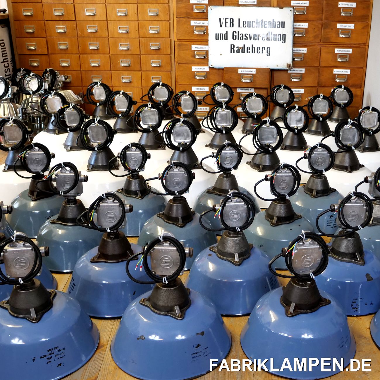 In den letzten Monaten ist Vieles passiert, ich habe wieder einige Bilder gemacht. 
Wir haben für ein Gastro-Projekt in Wien viele alte Industrielampen geliefert. Meistens handelt es sich hier um unsere Cervus-Lampen. Die Lampen existieren meist in blau/graublau und in weiß, in zwei Abmessungen. Für dieses Projekt haben wir weiße und blaue Lampen geliefert, letztere mit Absicht in unterschiedlichen Farbtönen – die alten Lampen wirken so wesentlich besser und spielerischer. Einige Bunkerlampen aus Aluminium sind auch mitgefahren. 
Die gusseisernen Köpfe sind aufgearbeitet und konserviert, auch die alten Aluminium Verteilerdosen sind erhalten geblieben. Die alten Industrielampen haben wir mit schwarzem Textilkabel montiert. 
Die Lampen haben wir sicher in Kartons verpackt und mit einer Direktlieferung per Spedition nach Wien geliefert. 
Wir kaufen natürlich auch viele Lampen, diese alten schwarzen Fabriklampen haben wir in München gefunden. Sie hingen in einem Gebäude bei BMW in der bayerischen Hauptstadt, das abgerissen worden ist. Ein Ingenieur hat es vor Ort gekauft, von ihm haben wir die Lampen erworben können. Die Lampen sind ordentlich verdreckt (das Gebäude stand lange leer), unter dem Staub und Farbresten sind sie aber weitestgehend gut erhalten. Sie stammen aus den 1930-er Jahren - in dieser Form und Anzahl sind sie heute kaum zu finden.  Nach der Restaurierung kommen sie auch auf unsere Seite, 4 haben wir bereits für ein Textilmuseum restauriert und geliefert. 
Alle Lampen, die eintreffen, lichte ich nicht ab, einige interessanten Posten aber immer wieder gerne. Hier eine Gruppe von Grünen Industrielampen. Vorne sind klassische Emaillelampen in verschiedenen Grüntönen zu sehen, der Durchmesser beträgt 31 cm. Die Fabriklampen haben das Herstellerlogo und die technischen Angaben, wie oft, in der Emaille. Der Durchmesser dieser Industrielampen beträgt 31 cm. In den hinteren Reihen sind alte Bunkerlampen zu sehen, die ebenfalls grüne Emailschirme haben. Diese Lampen sind in der Farbe eher selten. Sie haben das klassische gusseiserne Gehäuse, Glas und Gitter und sind mit diesen wirklich schönen grünen Emailschirmen sehr attraktiv. Die Erhaltung ist auch bei diesen Lampen hervorragend.  