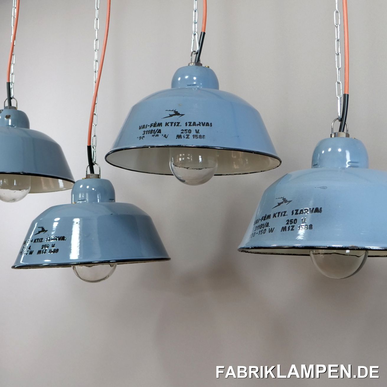  Alte Emaille Industrielampe aus den 1950er Jahren. Sehr seltene Ausführung mit großer Beschriftung und Schutzglas. Das Glas wird von dem in das Blech gepressten Gewinde gehalten. Bei diesem Typ haben die Leuchten in der Regel ein gusseisernes Gehäuse mit Gewinde, bei dieser Ausführung hat man Gehäuse und Schirm vereint. Sehr großes und schönes Typenschild in der Emaille mit dem Hirsch, Logo der Hersteller (genannt nach der Stadt, wo diese Leuchten damals produziert waren). 

Diese schönen Fabriklampen haben Spuren der vergangenen Jahrzehnte, wie Abplatzer, Roststellen, Kratzer, Verfärbungen und Co. Damit ist jede einzelne Lampe ein Unikat. 

Die Industrielampen sind restauriert: gereinigt, konserviert und neu elektrifiziert, mit neuen E27 Keramikfassungen.

Material: hellblau/graublau (innen weiß) emailliertes Stahlblech. 

Die Abmessungen: Höhe der Lampen ca. 20 cm (ohne Aufhängeöse), Durchmesser ca. 36 cm.  
Die alten Fabriklampen werden mit 2 Meter Kabel geliefert. Gegen Aufpreis können die Lampen auch mit Ketten- oder Stahlrohr-Aufhängung geliefert werden. Baldachine können wir auch anbieten.
 